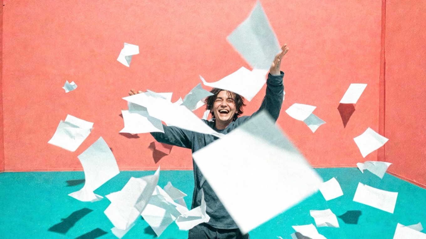 A person laughing and throwing papers into the air